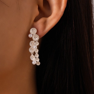 Close-up of silver tassel earrings with flower metal plates and pearls on model