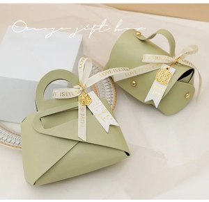 Detail of light green faux leather gift bag with gold charms and printed ribbon