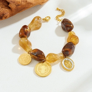 Vintage gold-plated bracelet with brown beads and religious medallions on white texture