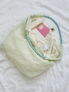 Light green canvas tote bag with white flower embroidery and blue braided handles