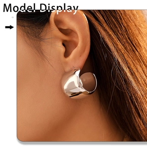 Polished silver C-shape chunky earrings worn by a model in a high-fashion editorial pose