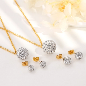 Detailed view of spherical gold zircon necklace and stud earrings set on white flowers