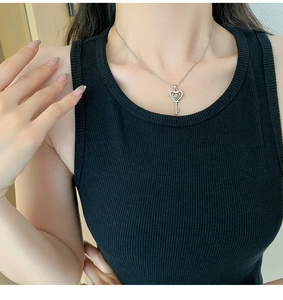 Détail du pendentif clé en cœur argenté avec pierre brillante sur une chaîne fine