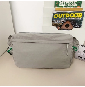 Waterproof nylon messenger bag in light grey with a green zipper pull detail