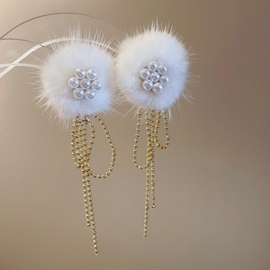 Detail of winter earrings with white pom-poms, pearl flowers and gold tassel chains