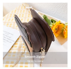 Detail of smooth zipper closure on dark brown cartoon house-shaped crossbody bag