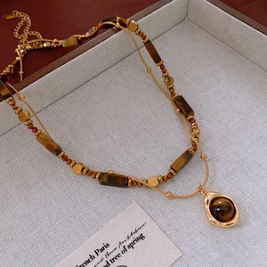 Detail of gold-plated double-layer necklace with tiger eye stone on jewelry box
