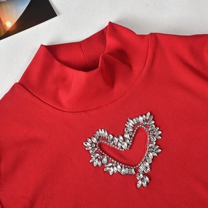Close-up of red ribbed knit top featuring a large sparkling rhinestone heart detail
