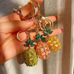 Close-up of opal pineapple keychains in green pink and yellow with gold-plated lobster clips
