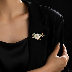 Detail of a lotus brooch with white shell petals and pink pearls on a black blazer