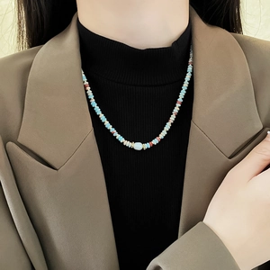 Close-up of a colorful beaded necklace with pearls on a model in a beige blazer