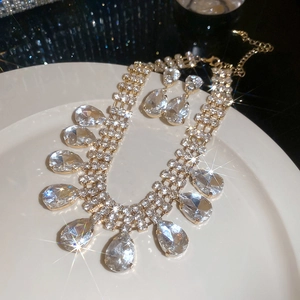 Detailed view of luxury gold necklace and earrings set with sparkling waterdrop crystals