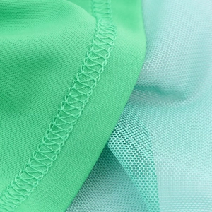 Detailed macro view of green knit and light cyan mesh fabric with fine overlock stitching