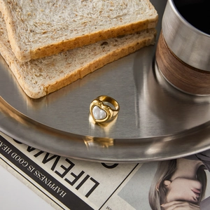 Detail of heart-shaped pearl ring in 18k gold finish on a vintage metal tray