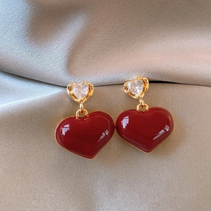 Detail of red enamel heart earrings with sparkling cubic zirconia on grey silk background