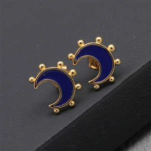 Détail macro de boucles d'oreilles lune dorées avec émail bleu et perles fines