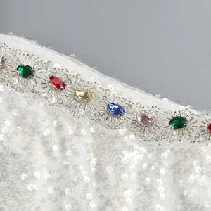 Detail of white sequin dress featuring colorful rhinestones and intricate beadwork embroidery