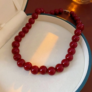 Close-up of a red round bead necklace presented in a luxury green velvet jewelry box