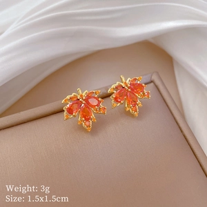 Macro shot of maple leaf earrings with orange zircons and measurement specs