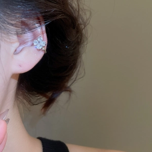 Close-up of elegant four-leaf clover ear cuff with zircon and pearl on female ear