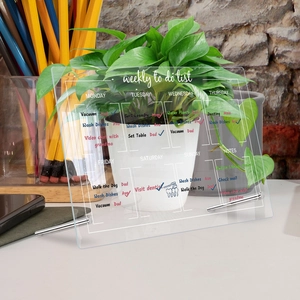 Transparent acrylic weekly planner on desk with metal stand and list detail