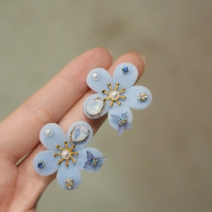 Close-up of light blue flocked flower earrings with pearls and sparkling crystals
