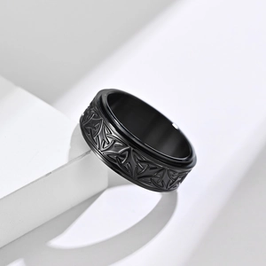 Detail shot of black matte Viking triquetra knot rotating ring on white geometry