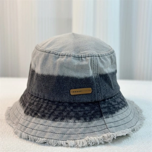 Close-up of gray gradient denim bucket hat featuring frayed edges and a branded logo patch