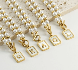 Detailed top view of gold OT buckle pearl necklaces with shell letter pendants Q K A G L
