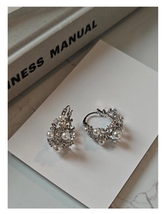 Detailed view of silver flower earrings with white pearls and sparkling cubic zirconia