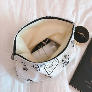 Close-up of waffle fabric makeup bag with black floral print and zip closure