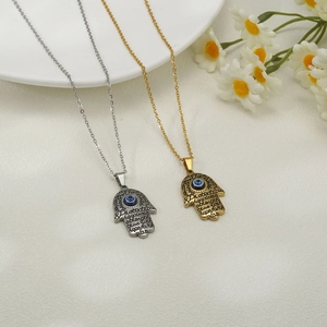 Detail of Hamsa Hand pendants in gold and silver with blue Evil Eye and engraved words
