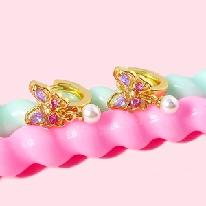 Détail de la boucle d'oreille papillon dorée avec cristaux et perle suspendue