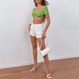 Detail of green ribbed crop top paired with white distressed denim shorts on model
