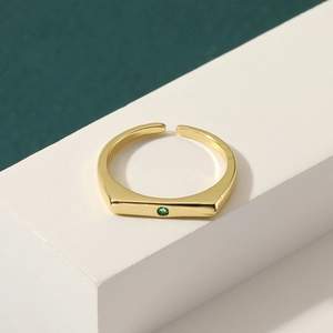 Minimalist gold geometric open ring with green zircon inlay on a white pedestal