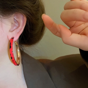 Close-up of a large red and black leopard print hoop earring worn by a model