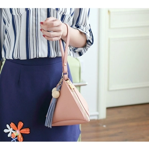 Detailed shot of pink leather triangle clutch with grey tassel and wooden bead charm