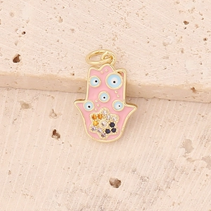 Macro view of a gold Hamsa Hand pendant with pink enamel and blue evil eye details