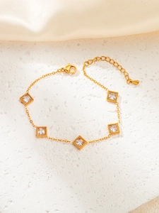 Macro detail of a gold chain bracelet with square cubic zirconia and milgrain edging