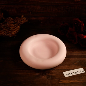 Top view of pink circular resin jewelry tray with rose and wood texture background