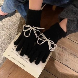 Close-up of black knit gloves with a large white pearl bow on a vintage book