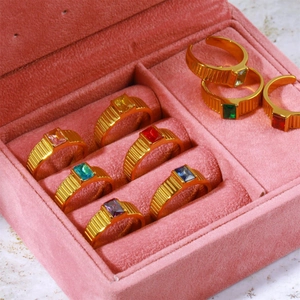 Golden birthstone rings with colorful gems displayed in a luxury pink velvet jewelry box