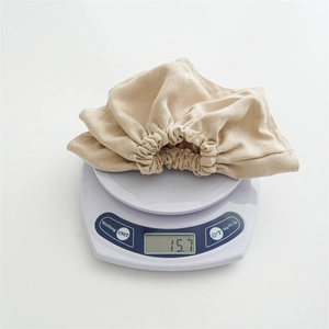 Lightweight 15.7g oversized beige fabric scrunchie shown on a digital scale