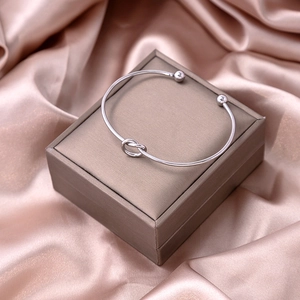 Detailed view of silver knot cuff bracelet on silk fabric inside a jewelry gift box