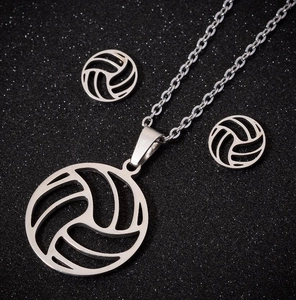 Detailed close-up of silver volleyball necklace and studs set on black background