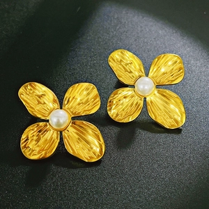 Detailed macro view of gold petal earrings with textured metal and central pearl inlay