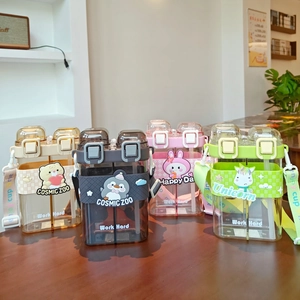 Detail view of four square double-compartment kids cups with straps in neutral colors