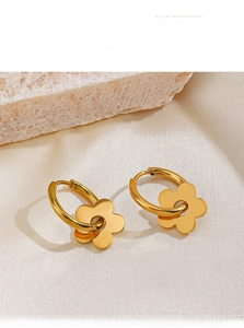 Détail de boucles d'oreilles fleur plaqué or 18K sur un tissu en satin crème
