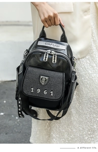 Detail of rhinestone 1961 logo and rivet accents on black soft leather backpack