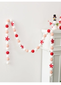 Detail of wool felt Christmas ball garland with candy cane style balls on white wall